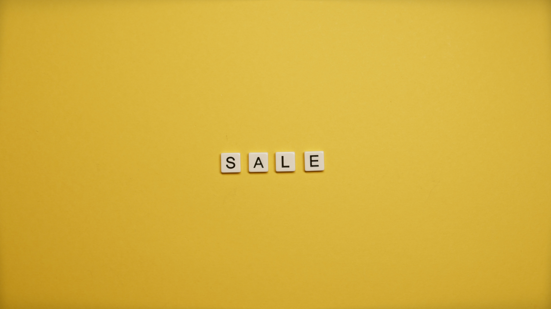 Single word 'SALE' spelled with tiles on a bright yellow background, ideal for advertising.