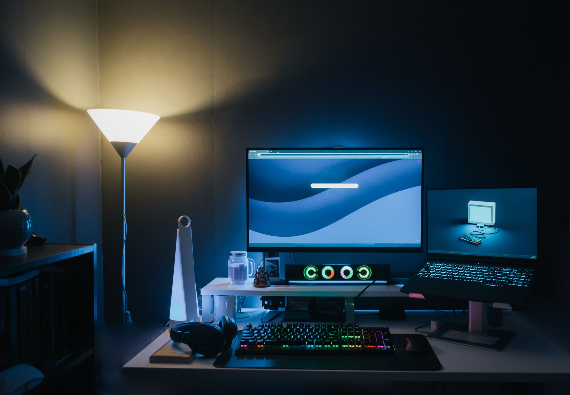 A stylish home office desk setup with dual monitors and ambient blue lighting.