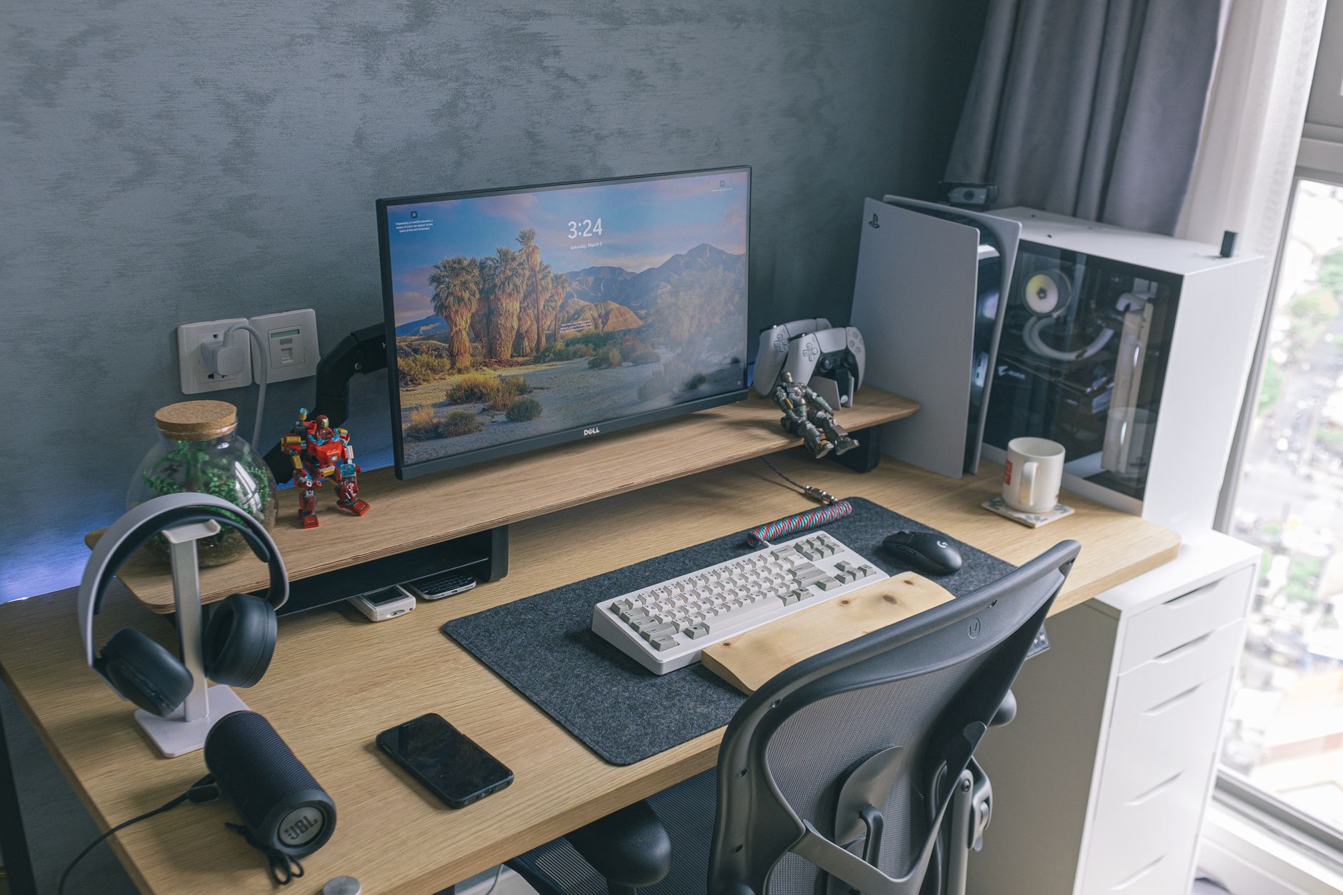 A sleek home office featuring a gaming console, monitor, keyboard, and desk accessories, ideal for technology enthusiasts.