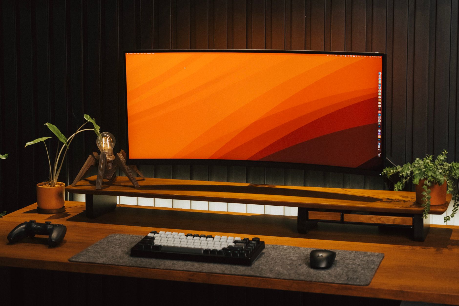 Curved monitor on a stylish desk with plants and tech accessories.