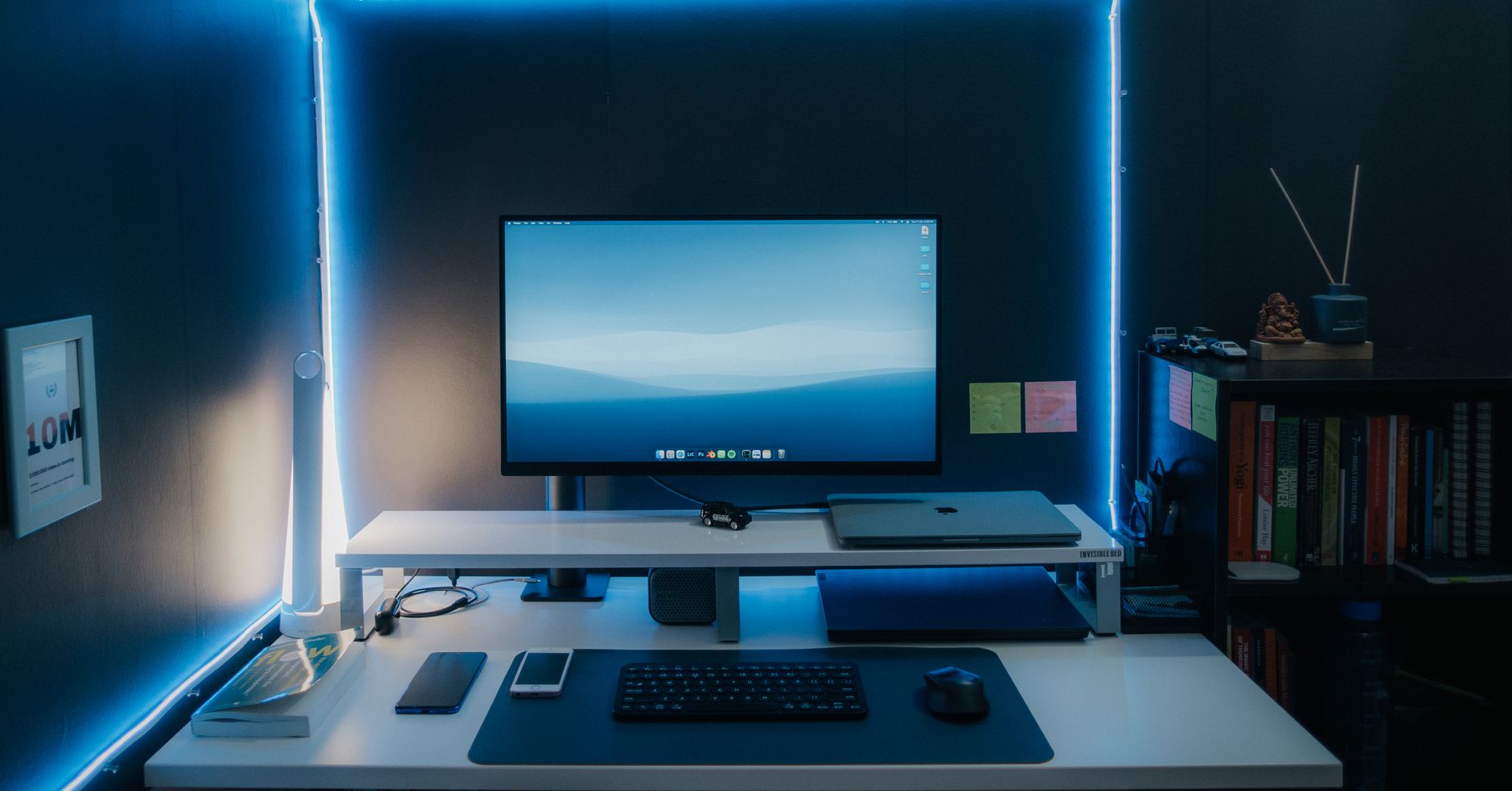Sleek home office setup with monitor, laptop, and LED lights, perfect for productivity.