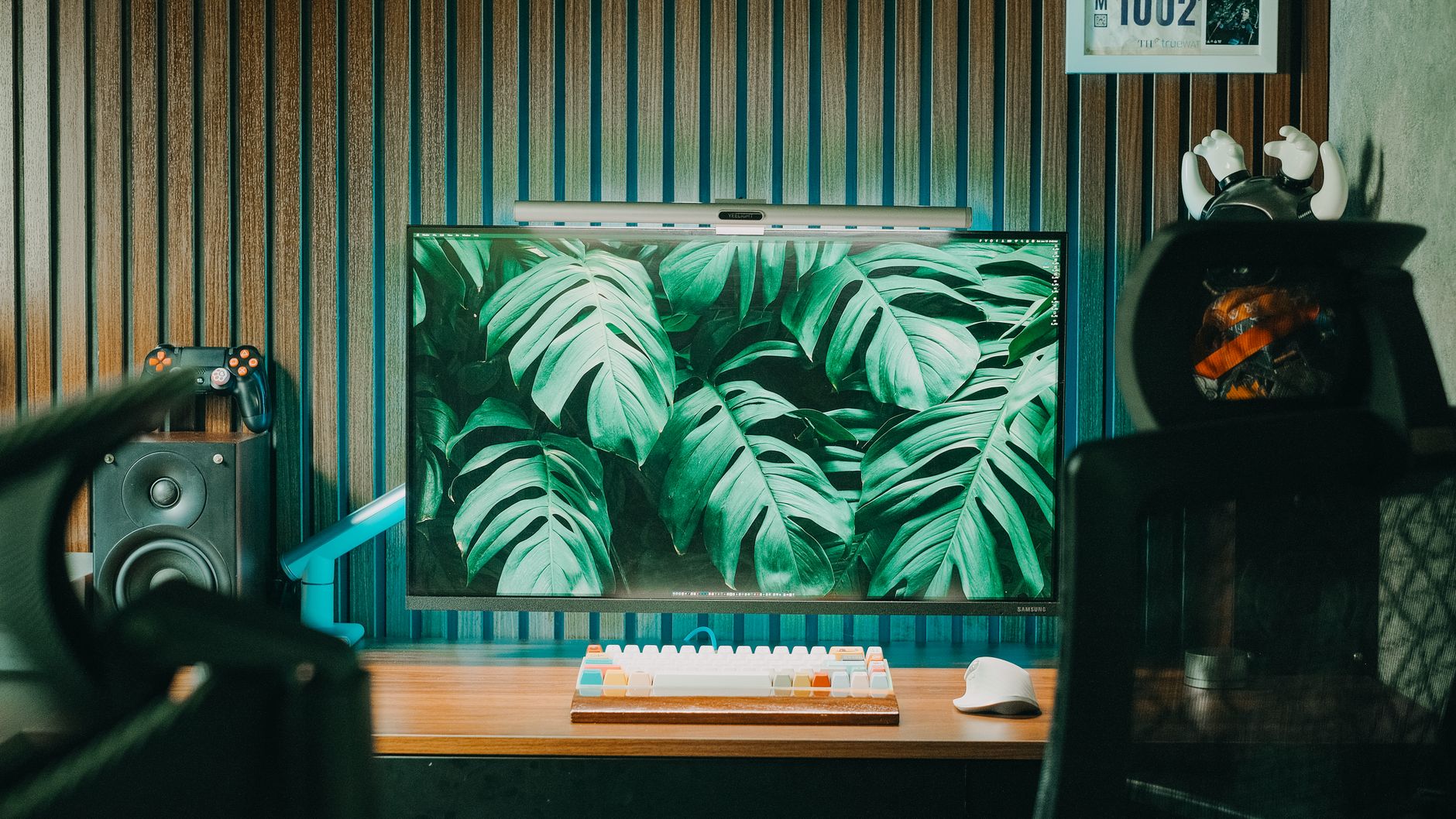 Modern home office with a stylish desk setup, featuring a monitor displaying green foliage.