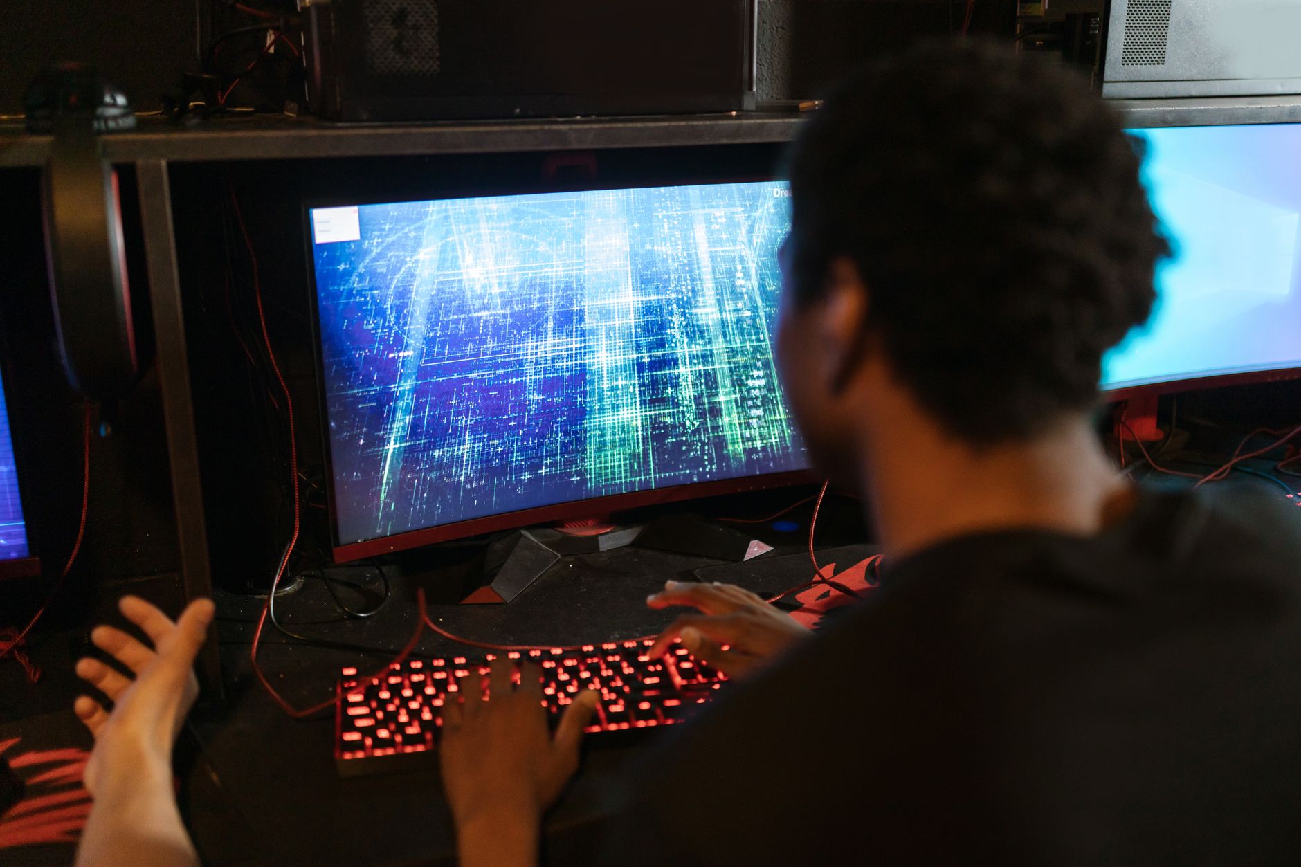 A man intensely engaged with a game on a multi-monitor setup in an esports setting.