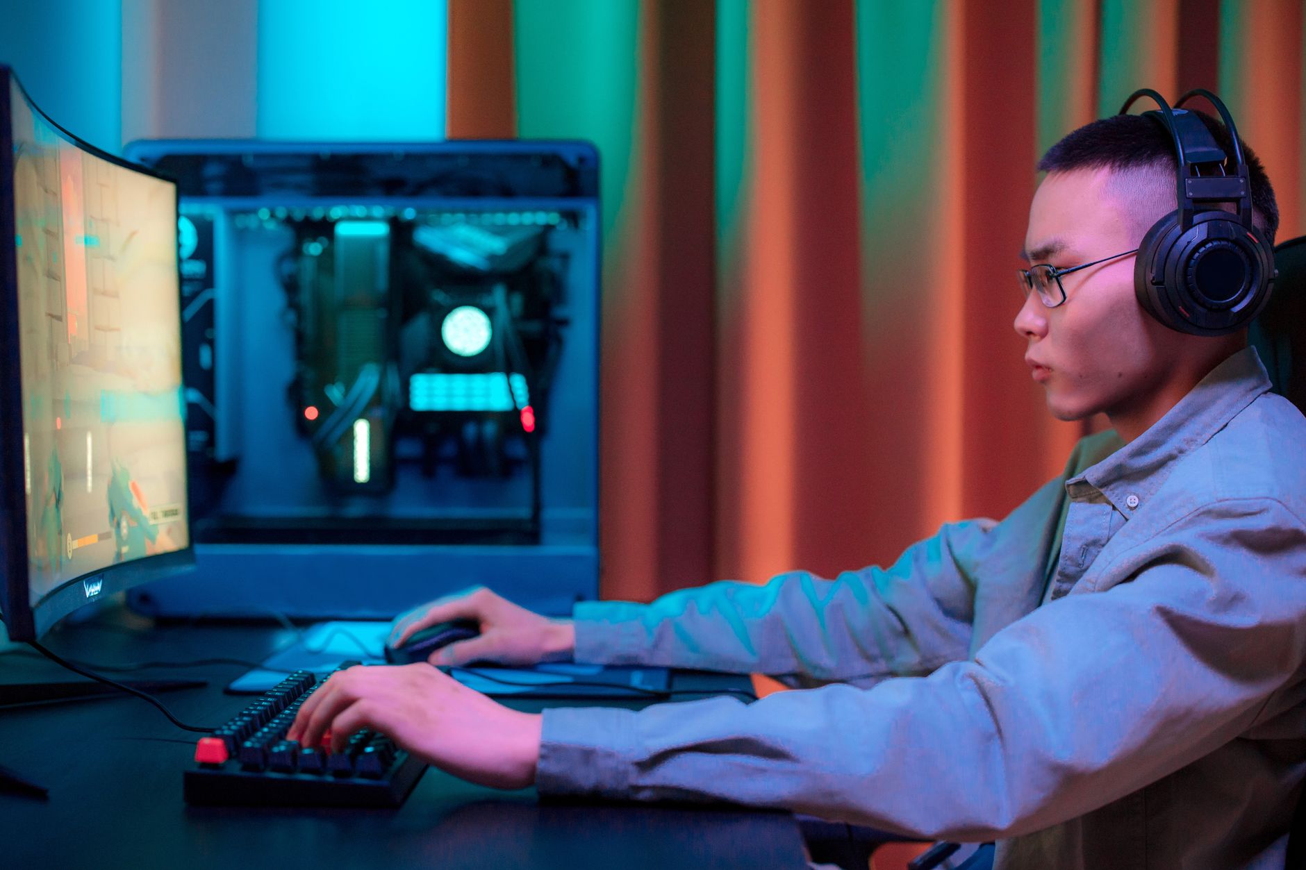 Intense gaming session of an adult male with headphones in a modern setup.