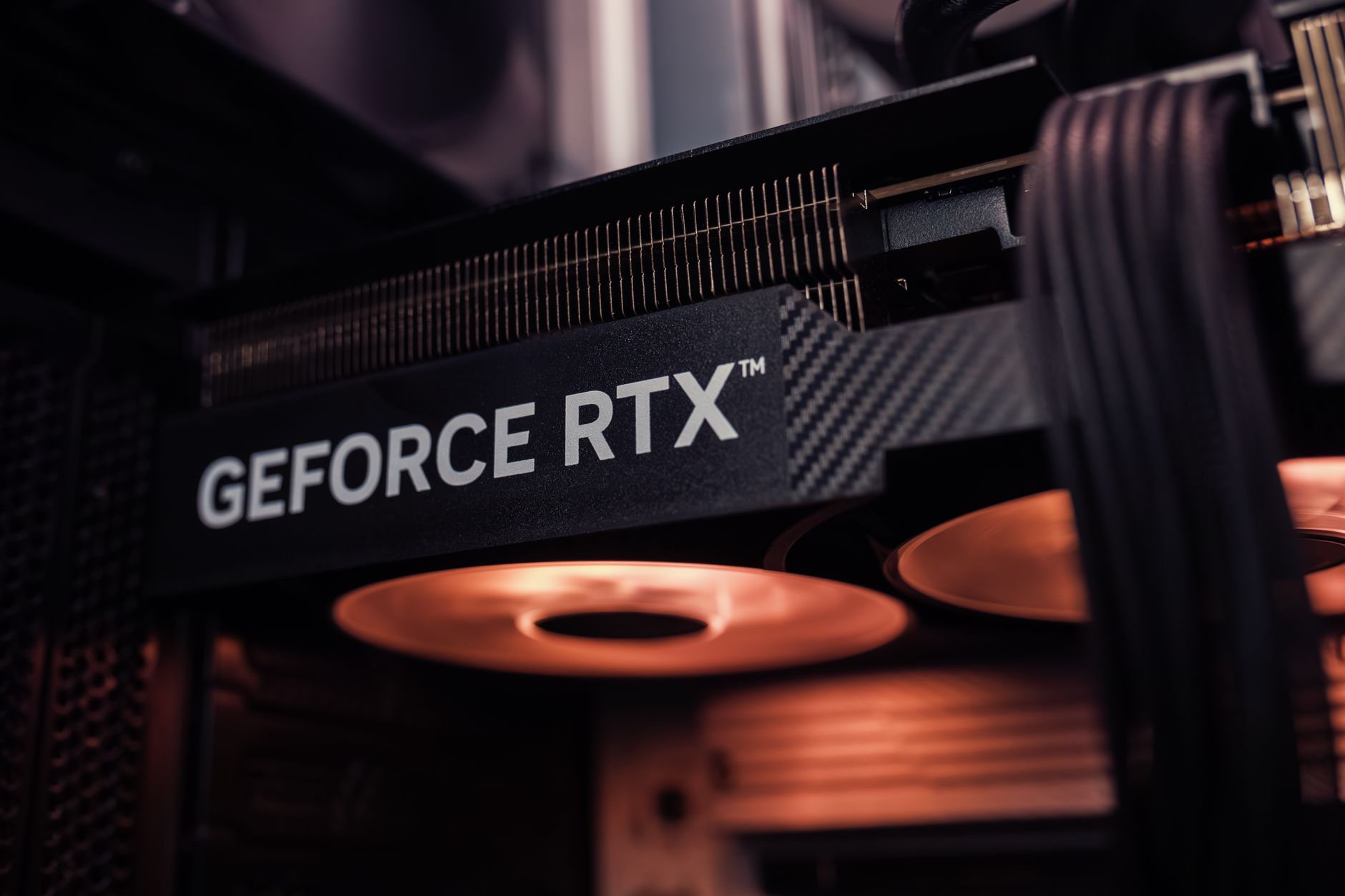 GeForce RTX graphics card installed inside a PC, glowing under warm lighting.