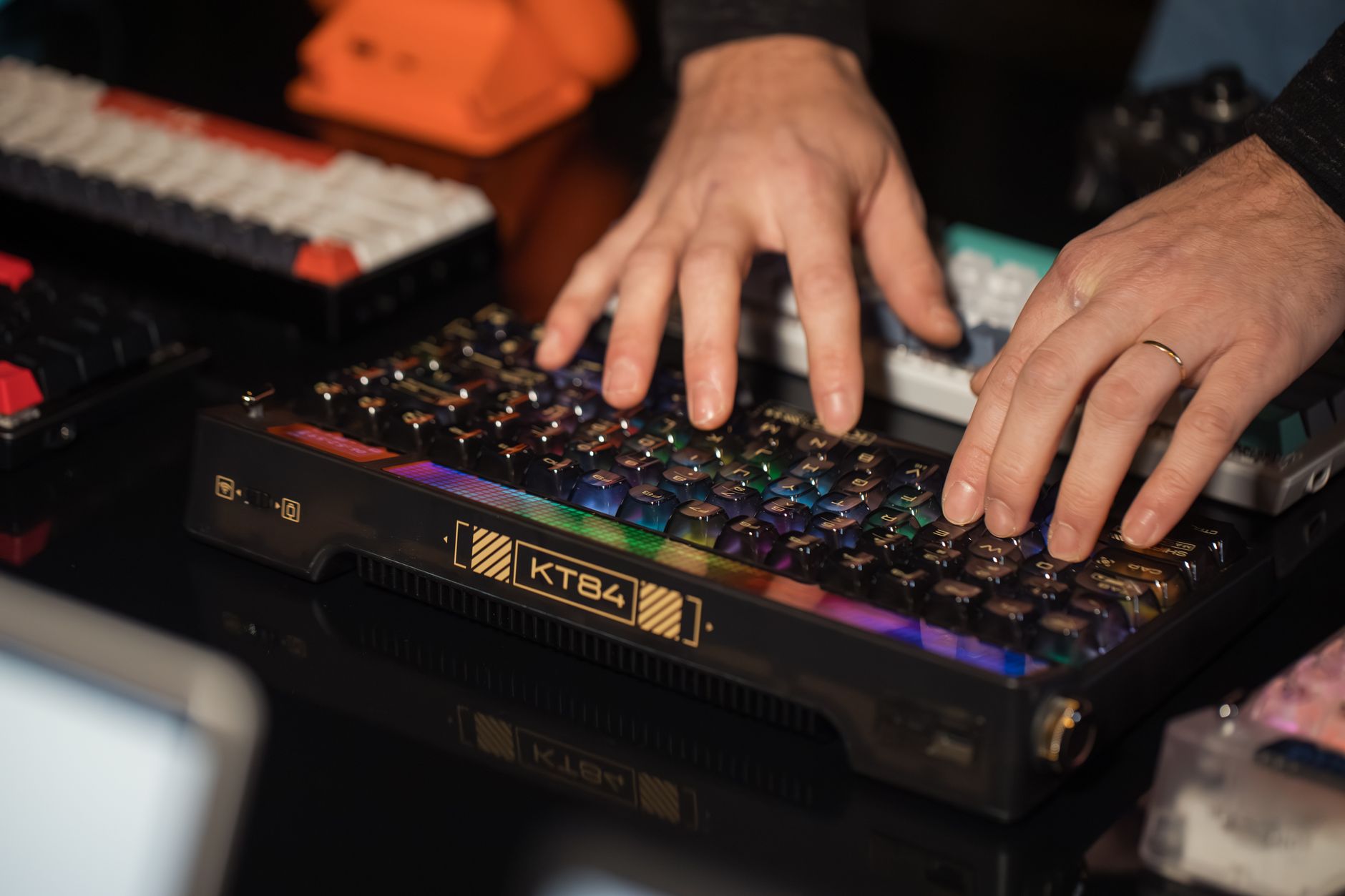 Hands typing on an RGB mechanical keyboard with colorful lights on a desk, creating a vibrant tech scene.