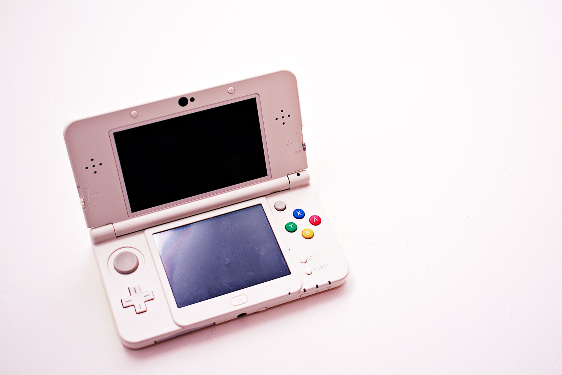 A clean shot of a white portable gaming console with two screens.