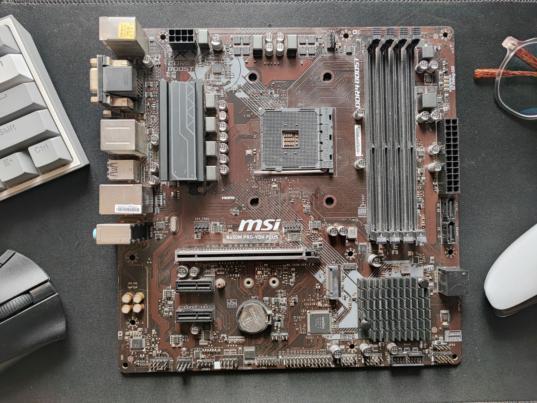 Close-up photo of an MSI B450M Pro-Vdh Plus motherboard on a desk.