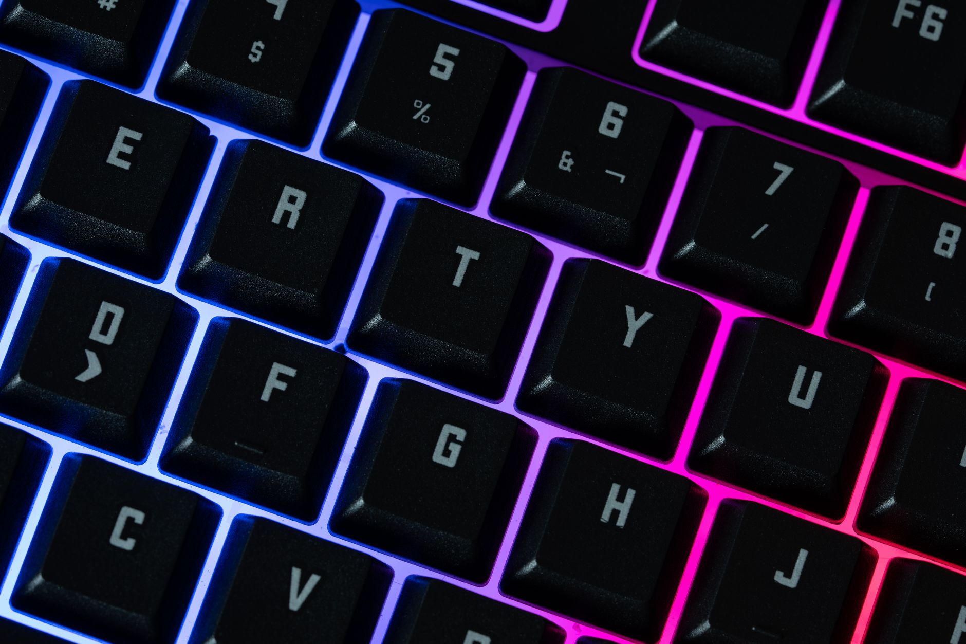 Detailed view of an RGB mechanical keyboard featuring vivid neon lighting and backlit keys.