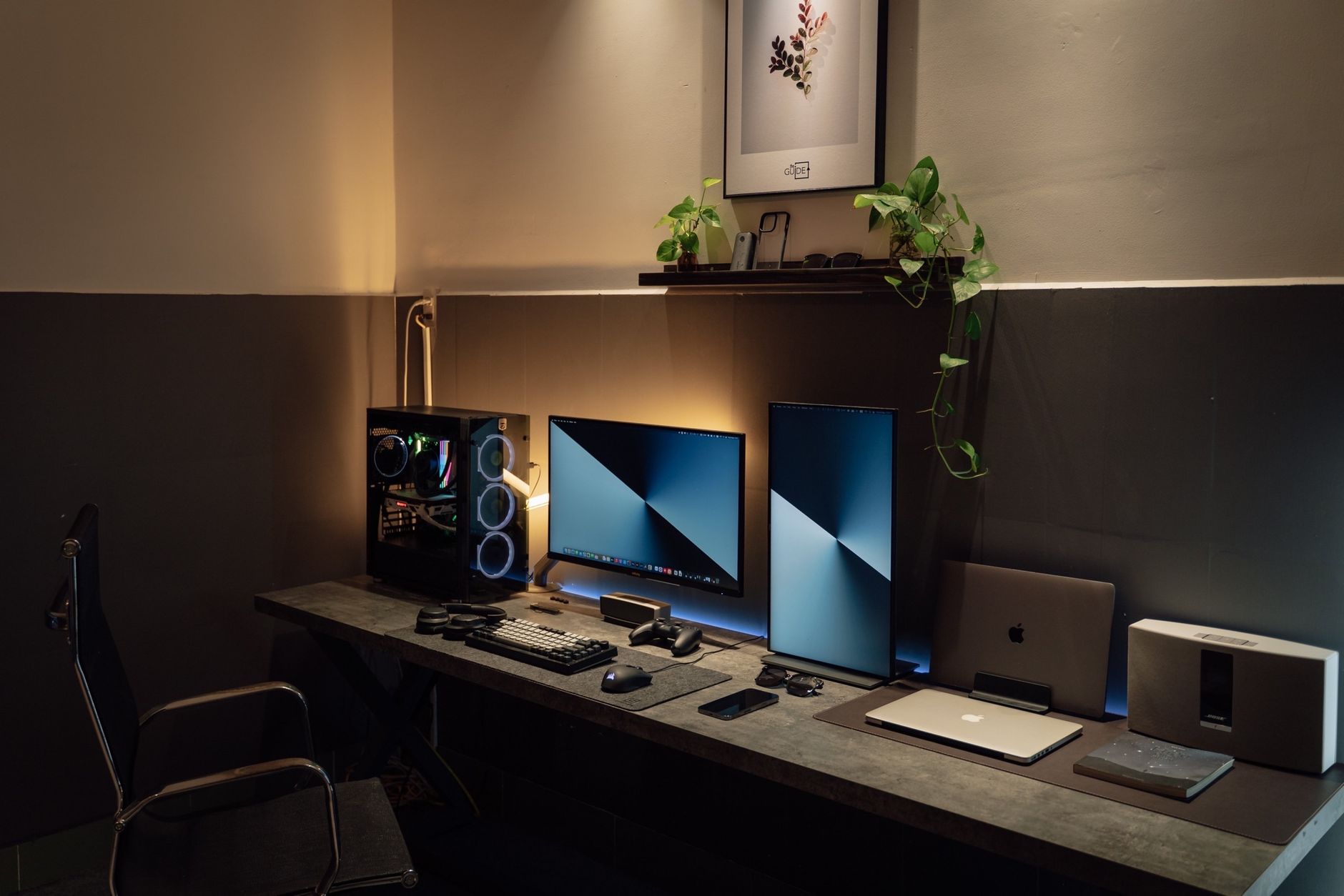 A sleek and modern desk setup featuring dual monitors, gaming PC, and tech gadgets in a well-lit room.