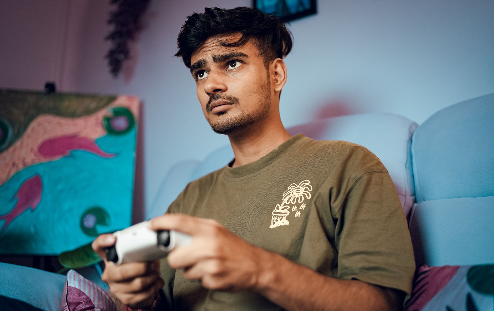 A young man intensely focused on playing video games at home with a controller.