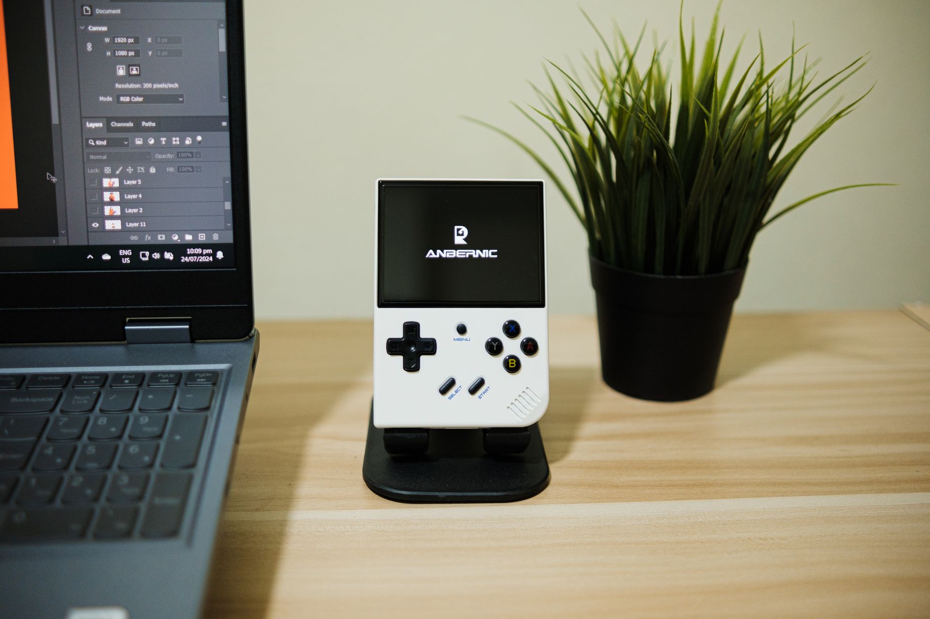 A sleek desktop with a laptop, handheld console, and a plant. Perfect blend of technology and nature.